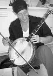 LAYLI WHYTE Jon Francis plays a tune on his banjo with a violin bow. Some of his recycled homemade instruments are displayed below. 