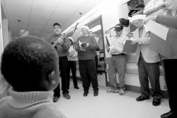A group of carolers (above) sings Christmas songs for Matthew Lavarin at Monmouth Medical Center in Long Branch on Dec. 15. Left, Michael Ellis plays guitar and leads the carolers through the hospital&rsquo;s hallways. He has made the caroling an annual event at local hospitals for more than 20 years.  