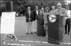 PHOTOS BY VERONICA YANKOWSKI  East Brunswick Mayor William Neary (top) speaks during a press conference Monday in front of Sam&rsquo;s Club, Route 18 near Tices Lane.  At right, Furs by Guarino, across Route 18 from Highland Street, is in the direct path of a plan to connect a new road, jughandle and traffic light.