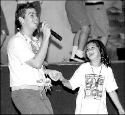 JERRY WOLKOWITZ Sarah Schindler of Camp Ramah, East Brunswick, enjoys a dance with a singer from the Israel Scouts Friendship Caravan, which performed at the camp on Ryders Lane Aug. 14.