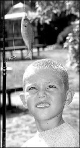 Dominic Christiana, 6, watches his fish flop around while he waits his turn to measure and weigh it.