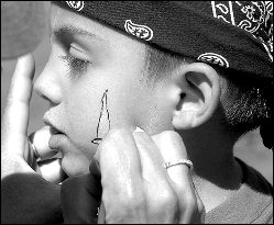 At right, Tyler Cree, 5, has a sword painted on his face during the festival.