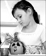 Six-year-old Stephanie Holtje of Monroe paints a pumpkin during the 14th annual Monroe Country Fair in Thompson Park Sunday.
