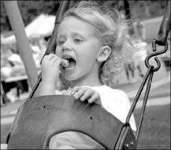 FARRAH MAFFAI Nicole DeKok, 3, enjoys some cotton candy on the swing during Pride In Milltown Day Saturday.