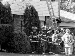 JERRY WOLKOWITZ Firefighters from several companies gather in front of a house on Sullivan Way in East Brunswick, where police believe a burglar started a fire Monday.
