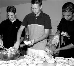 FARRAH MAFFAI Casey Conger, (l-r) Rick Rosenberg Jr. and Raja Krishnamathy, members of the community service group South River Students for the Enhancement of the Community, serve dinners at the Holy Trinity Episcopal Church, located on Leonardine Avenue, last Thursday.