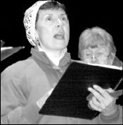 PHOTOS BY FARRAH MAFFAI Kate Mallard, above, sings with the East Brunswick Community Chorus during the sixth annual East Brunswick Holiday Celebration Monday night. Michelle Noonan, 2, (inset), plays with her glow stick during the holiday celebration at the East Brunswick municipal complex Monday night.