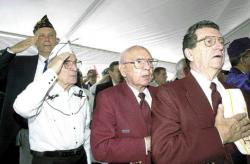 FARRAH MAFFAI Bob Richards (top, left), commander of Milltown  American Legion Post 25, says the Pledge of Allegiance at a Purple Heart stamp ceremony Friday. Also pictured: former state Finance Officer Bill Kaye, former POWs Stewart Cooper and Zack Roberts.