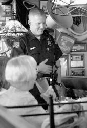 VERONICA YANKOWSKI Patrolman Christopher Witt visits a table at Applebee&rsquo;s Thursday evening.