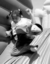 PHOTOS BY FARRAH MAFFAI  At right, Charity Jackson, 7, slides down the end of a blow-up toy known as the &ldquo;Beach Party Olympics&rdquo; during Fun Day Friday.