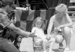 JERRY WOLKOWITZ At right, East Brunswick resident Ciara Gaertner, 4, thanks lumberjack Dave Weatherhead for carving the wooden chair she&rsquo;s sitting in during a demonstration at the fair last week.