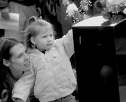 SCOTT FRIEDMAN With help from her mom Amy, 2-year-old Zoe Koch places a rose on her father's memorial stone outside Our Lady of Lourdes School, Milltown, on Saturday. 