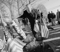 PHOTOS BY JEFF GRANIT staff Monroe Mayor Richard Pucci (l), places a wreath on the Veterans Monument at the township's municipal complex Tuesday in honor of Veterans Day. Earlier Tuesday, officials held a ceremony at the Triangle Memorial on Spotswood Englishtown Road. Above, American and POW-MIA flags fly high as local veterans head off after the ceremony. 
