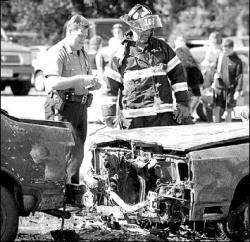 JERRY WOLKOWITZ  Freehold Township Patrolman Brian Worth and a member of East Freehold Fire Company look over the aftermath of a vehicle fire that occurred in the parking lot of the YMCA of Western Monmouth County, East Freehold Road, July 12. Three vehicles were damaged when a fire started in a car belonging to an Old Bridge resident. The Monmouth County fire marshal said the origin of the fire was possibly electrical. No one was injured.