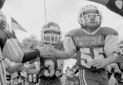 PHOTOS BY SCOTT FRIEDMAN At left, Daniel O'Connor (r) and Matthew Bordfeld lead their team onto the field at the Freehold Pop Warner Mitey Mites football game between Freehold and Matawan on Sunday. At right, Noah Powell drags several defenders as he struggles to gain a few extra yards against Matawan. 