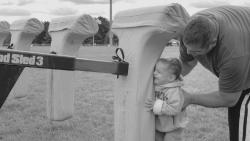 21-month-old Vincent Ranaudo gets a lesson on hitting the sled from his dad, Virgil, at Sunday's Freehold Pop Warner Mitey Mites game. 